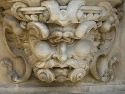 Barockes Steinrelief mit Maskaron (Dämonengesicht), eingerahmt von Voluten